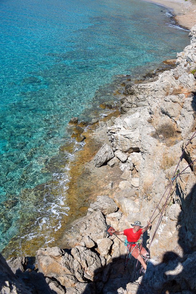 Person routesetting climbing routes with a Hilti drill at the Mazida beach, Xerokampos, east Crete